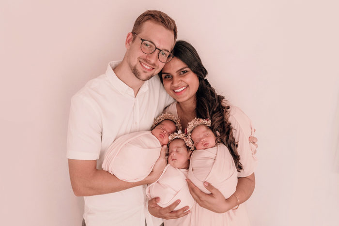 Suesse Drillinge liegen im Arm ihrer Eltern beim Neugeborenen Shooting in Duesseldorf fotografiert von Babyfotografin