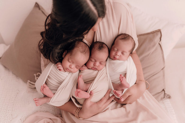 Suesse Drillinge liegen im Arm ihrer Mama beim Neugeborenen Shooting in Duesseldorf fotografiert von Babyfotografin