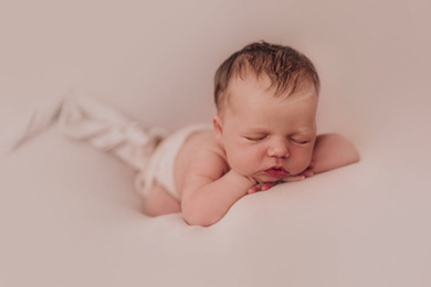 Baby liegt auf dem Bauch und wird beim Neugeborenenshooting von Babyfotografin Duesseldorf fotografiert