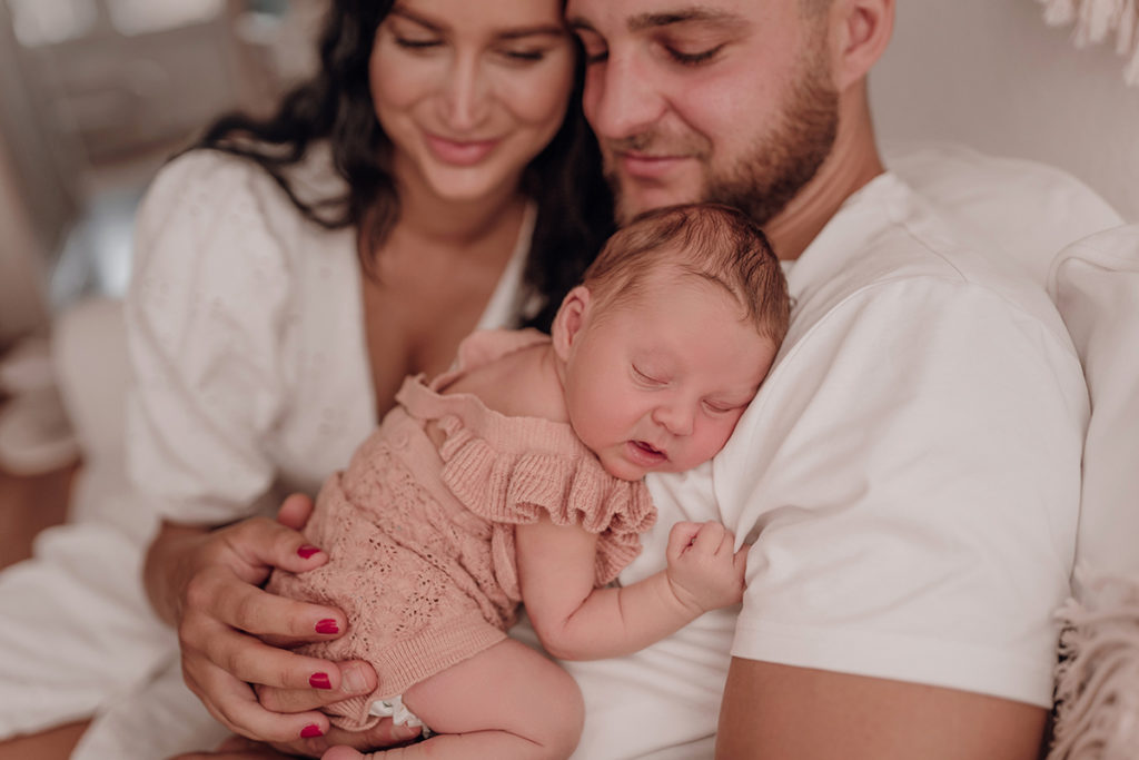 Neugeborenes Baby schläft auf dem Arm seines Papas beim Neugeborenen Shooting mit einfallslicht fotografie Babyfotografin Düsseldorf