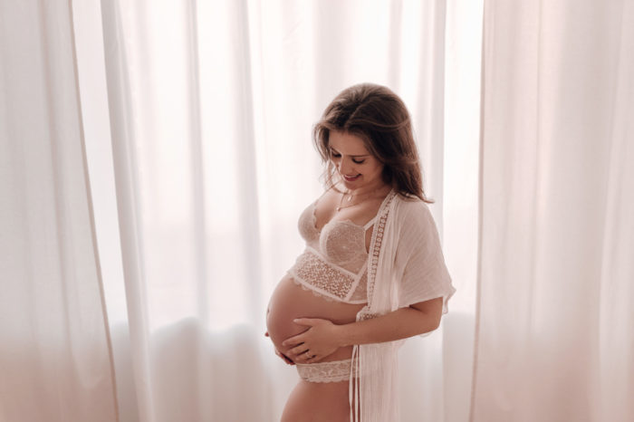 Mama streichelt Babybauch Babybauchfotos im Studio Babybauchsession Duesseldorf Babyfotos Babyfotografin Düsseldorf Umstandkleid Schwangerschaftskleid