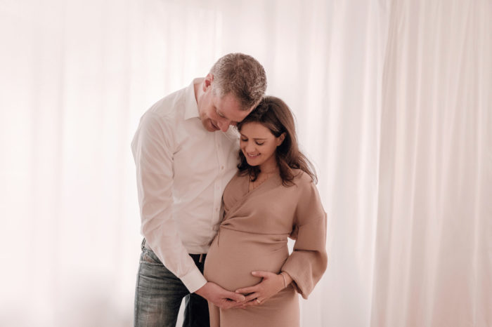 Mama und Papa streicheln Babybauch Babybauchfotos im Studio Babybauchsession Duesseldorf Babyfotos Babyfotografin Düsseldorf Umstandkleid Schwangerschaftskleid