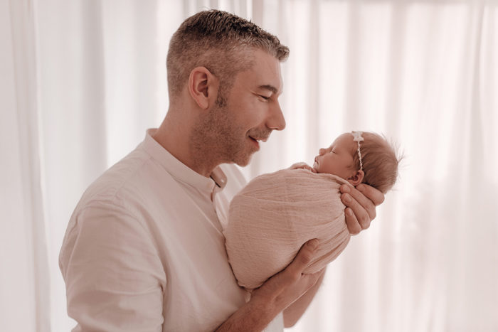 Papa küsst Baby beim Neugeborenen Shooting, Geschwisterliebe, Familienshooting bei einfallslicht fotografie in Düsseldorf, Baby, Babykleidung, Babybody