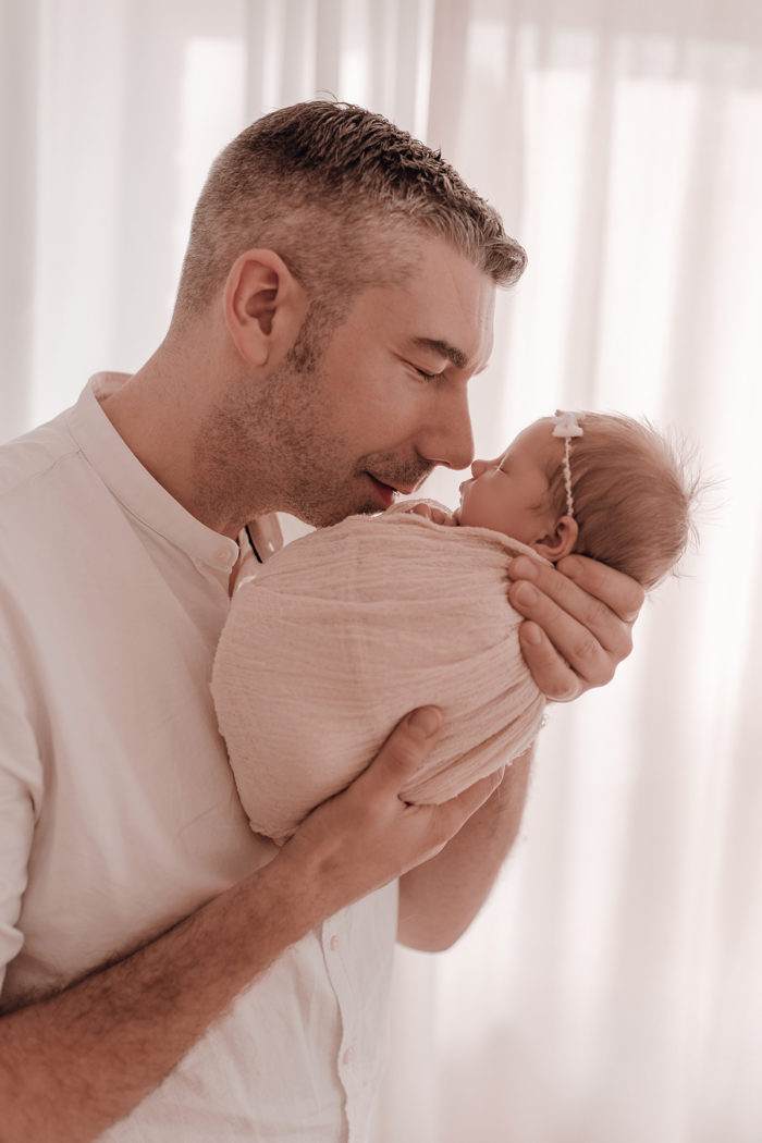Papa küsst Baby beim Neugeborenen Shooting, Geschwisterliebe, Familienshooting bei einfallslicht fotografie in Düsseldorf, Baby, Babykleidung, Babybody